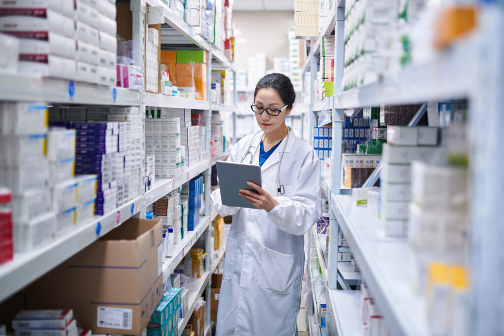 Asian Female Pharmacist Using Digital Tablet while Taking Inventory