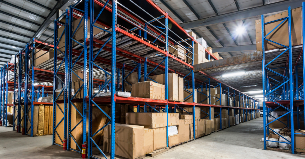 Warehouse aisle with tall pallet racking storing boxed inventory and packaging materials on multiple shelf levels