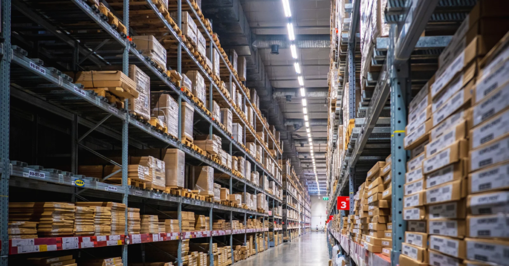 Warehouse aisle with tall storage racks filled with palletized boxes and labeled inventory