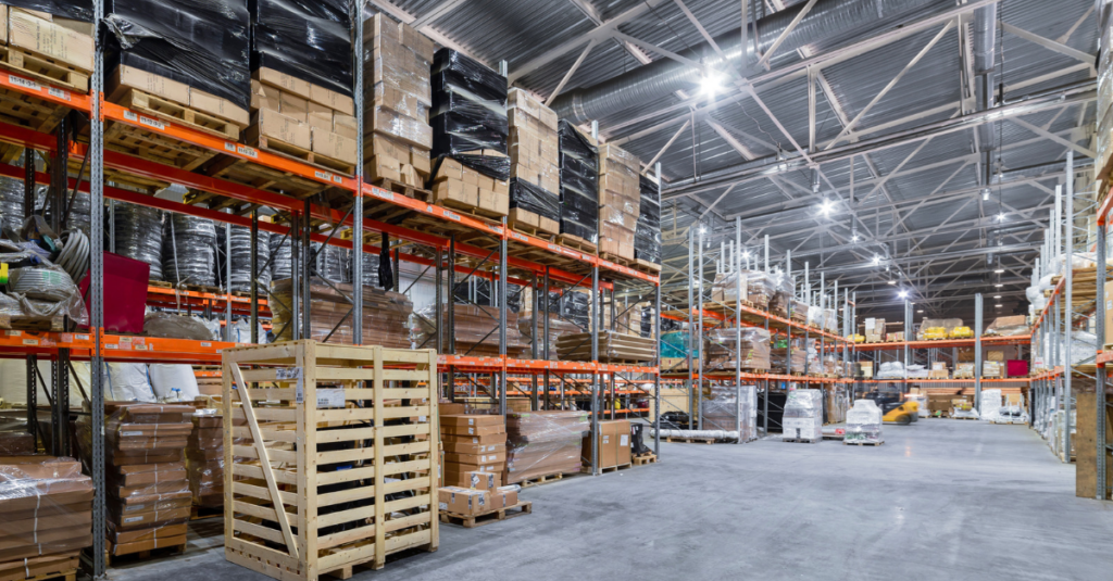 Warehouse aisle with tall pallet racking storing boxed inventory, pallets, and packaged materials on industrial shelving