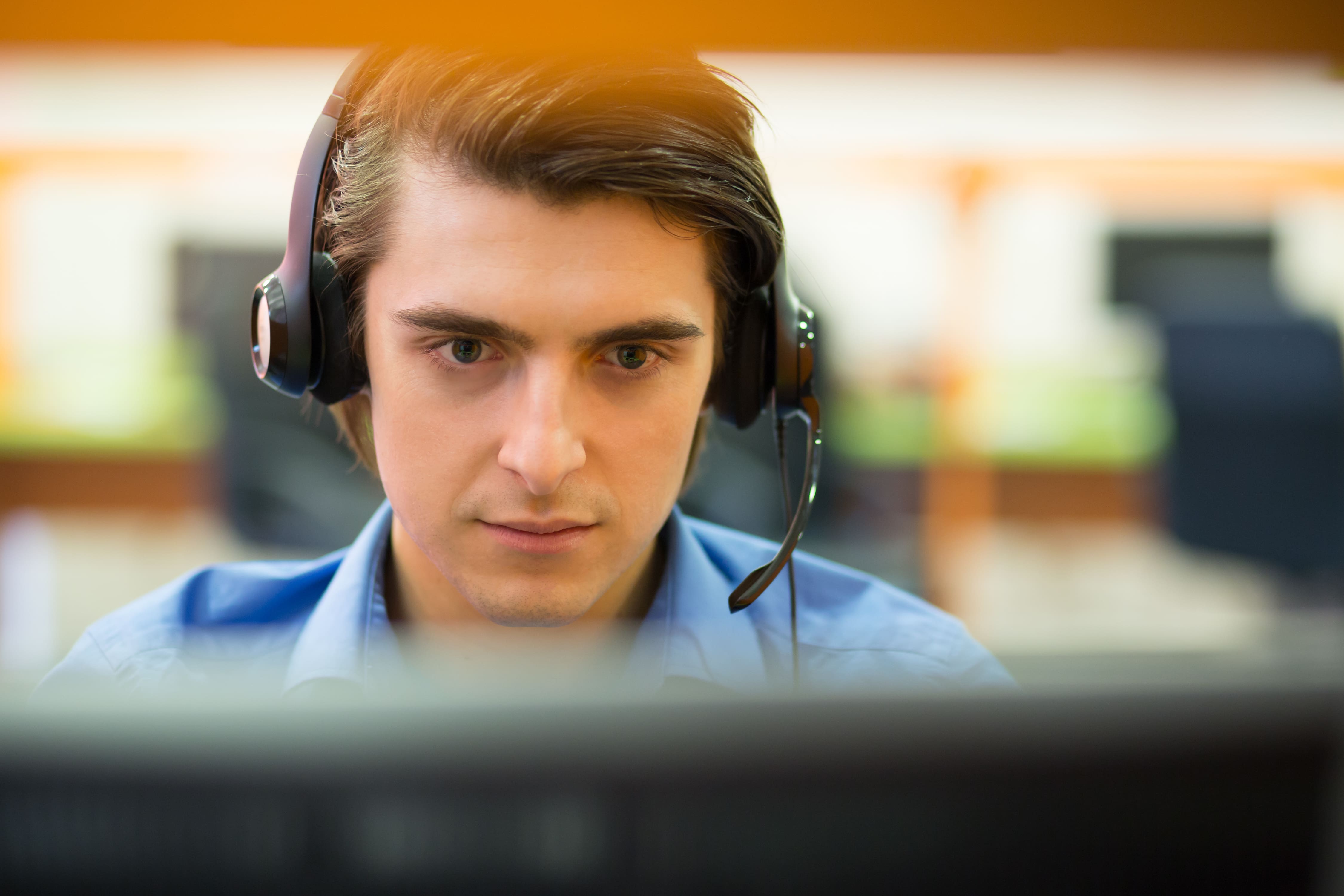 Young customer service operator talking on headset, smiling.