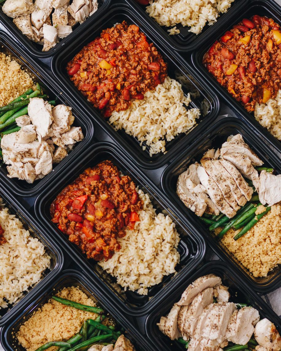 Meal prep containers filled with seasoned rice, chicken, and vegetables in a grid layout